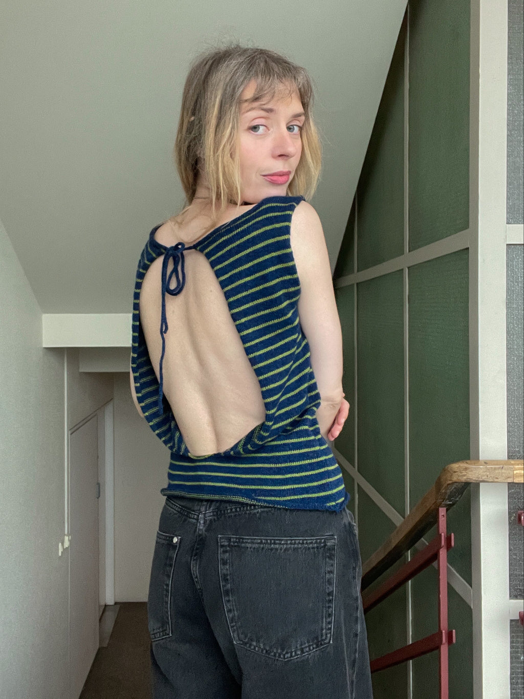 Person wearing a blue striped top with a beige back panel in an indoor setting